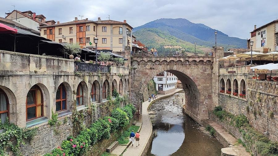 Puente de piedra sobre el río Quiviesa con el casco viejo de Potes